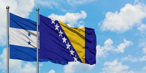 Honduras and Bosnia Herzegovina flag waving in the wind against white cloudy blue sky together....
