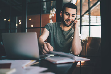 Smiling man chatting on phone and working