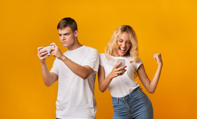 Excited youngsters playing on smartphones, having fun together