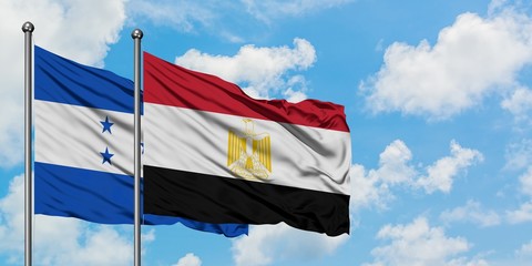 Honduras and Egypt flag waving in the wind against white cloudy blue sky together. Diplomacy concept, international relations.