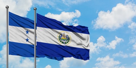 Honduras and El Salvador flag waving in the wind against white cloudy blue sky together. Diplomacy...