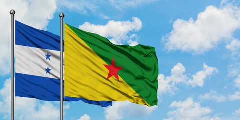 Honduras and French Guiana flag waving in the wind against white cloudy blue sky together. Diplomacy concept, international relations.