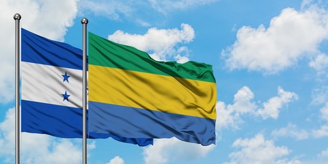 Honduras and Gabon flag waving in the wind against white cloudy blue sky together. Diplomacy...