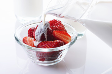 Cream flows on strawberry. White background. High key. Close up. Selective focus.