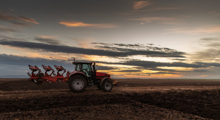 Tractor plowing fields in sunset