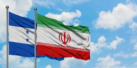 Honduras and Iran flag waving in the wind against white cloudy blue sky together. Diplomacy concept, international relations.