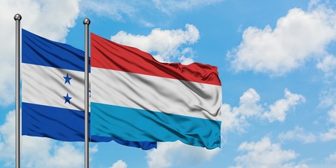 Honduras and Luxembourg flag waving in the wind against white cloudy blue sky together. Diplomacy...