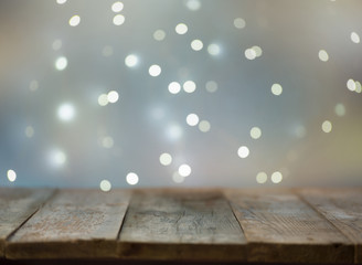 Image of old wooden dark table in front of background with shimmering bokeh light. The product is...