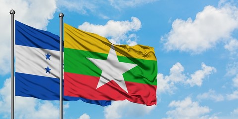 Honduras and Myanmar flag waving in the wind against white cloudy blue sky together. Diplomacy...