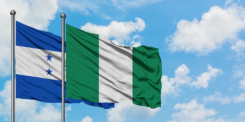Honduras and Nigeria flag waving in the wind against white cloudy blue sky together. Diplomacy...