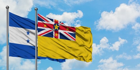 Honduras and Niue flag waving in the wind against white cloudy blue sky together. Diplomacy...