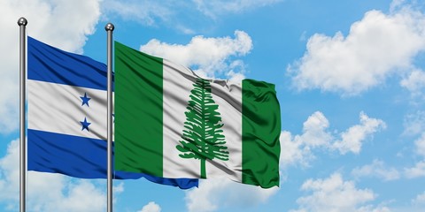 Honduras and Norfolk Island flag waving in the wind against white cloudy blue sky together....