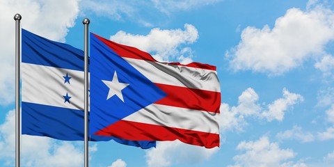 Honduras and Puerto Rico flag waving in the wind against white cloudy blue sky together. Diplomacy concept, international relations.