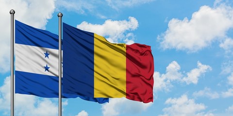 Honduras and Romania flag waving in the wind against white cloudy blue sky together. Diplomacy concept, international relations.