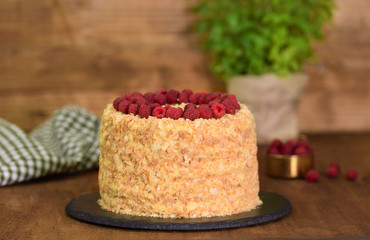 Delicious homemade Napoleon layered cake with raspberries on a wooden table.