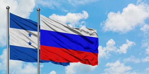 Honduras and Russia flag waving in the wind against white cloudy blue sky together. Diplomacy concept, international relations.