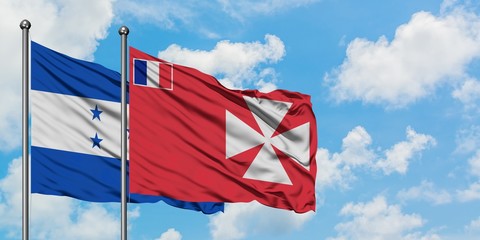 Honduras and Wallis And Futuna flag waving in the wind against white cloudy blue sky together....