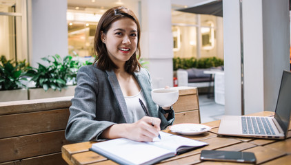 Happy freelancer taking notes while looking at camera