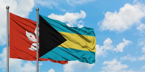 Hong Kong and Bahamas flag waving in the wind against white cloudy blue sky together. Diplomacy concept, international relations.