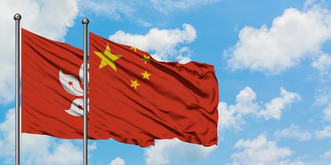 Hong Kong and China flag waving in the wind against white cloudy blue sky together. Diplomacy...