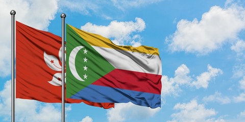 Hong Kong and Comoros flag waving in the wind against white cloudy blue sky together. Diplomacy...