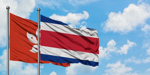 Hong Kong and Costa Rica flag waving in the wind against white cloudy blue sky together. Diplomacy concept, international relations.