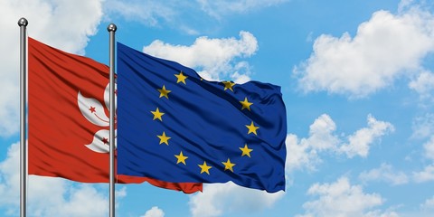 Hong Kong and European Union flag waving in the wind against white cloudy blue sky together....