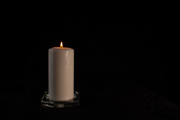 burning white candle on a black background, copy space