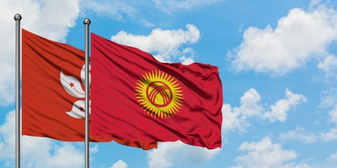 Hong Kong and Kyrgyzstan flag waving in the wind against white cloudy blue sky together. Diplomacy...