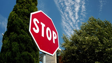 Octagonal STOP sign on a red background with blue sky with clouds. conceptual photo