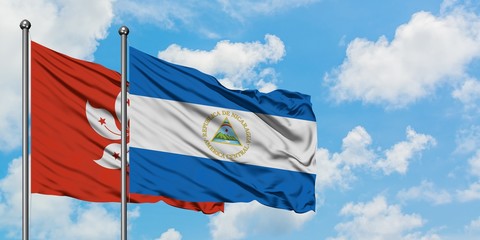 Hong Kong and Nicaragua flag waving in the wind against white cloudy blue sky together. Diplomacy...