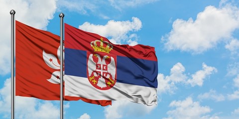 Hong Kong and Serbia flag waving in the wind against white cloudy blue sky together. Diplomacy concept, international relations.