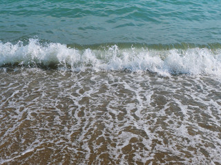 Closeup of sea wave with surf and foam. Natural movement of sea water. Game of sun glare on sea foam. Marine concept. High shutter speed fixation, front view, low angle, horizontal composition