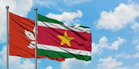 Hong Kong and Suriname flag waving in the wind against white cloudy blue sky together. Diplomacy concept, international relations.