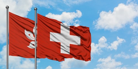 Hong Kong and Switzerland flag waving in the wind against white cloudy blue sky together. Diplomacy...