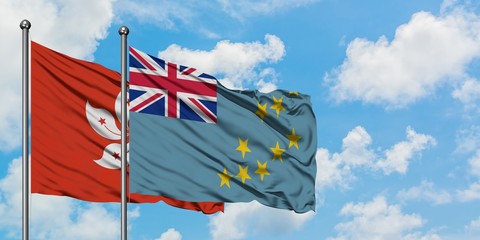 Hong Kong and Tuvalu flag waving in the wind against white cloudy blue sky together. Diplomacy...