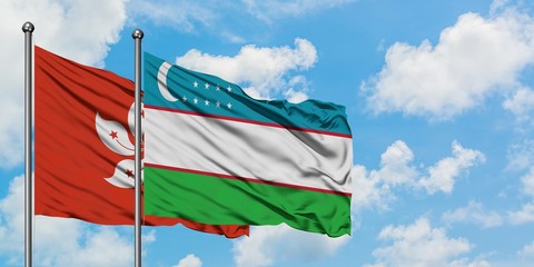 Hong Kong and Uzbekistan flag waving in the wind against white cloudy blue sky together. Diplomacy concept, international relations.