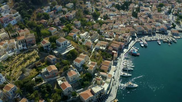 Aerial bird's eye view video taken by drone of beautiful picturesque houses with views to port of Symi island, Dodecanese, Greece.