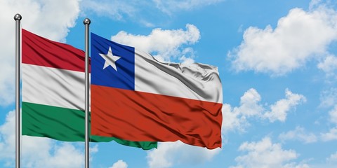 Hungary and Chile flag waving in the wind against white cloudy blue sky together. Diplomacy concept, international relations.