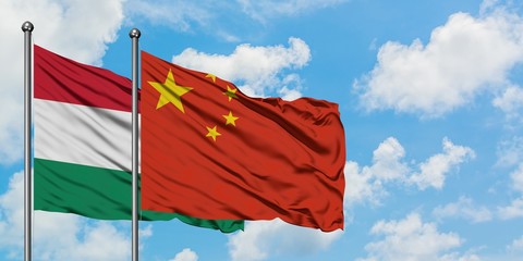 Hungary and China flag waving in the wind against white cloudy blue sky together. Diplomacy concept, international relations.