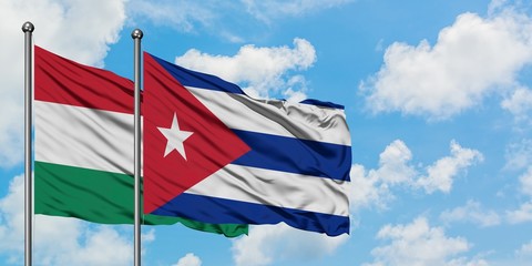 Hungary and Cuba flag waving in the wind against white cloudy blue sky together. Diplomacy concept, international relations.