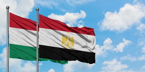 Hungary and Egypt flag waving in the wind against white cloudy blue sky together. Diplomacy concept, international relations.