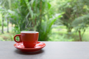 Red coffee cup on wooden table and natural background