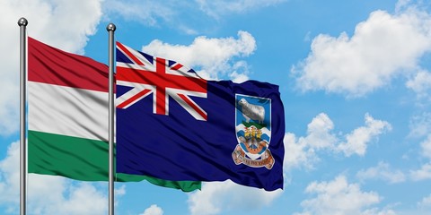 Hungary and Falkland Islands flag waving in the wind against white cloudy blue sky together....