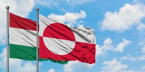 Hungary and Greenland flag waving in the wind against white cloudy blue sky together. Diplomacy concept, international relations.