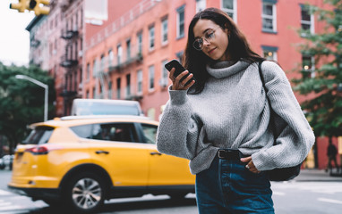 Fototapeta premium Concentrated woman browsing smartphone on city street