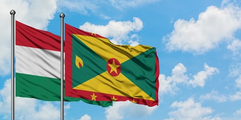 Hungary and Grenada flag waving in the wind against white cloudy blue sky together. Diplomacy concept, international relations.