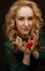 Beautiful resilient young girl holding a strawberry. Portrait in the studio background