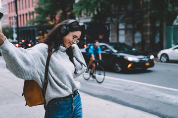 Young female walking on sidewalk and listening music