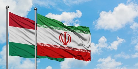 Hungary and Iran flag waving in the wind against white cloudy blue sky together. Diplomacy concept,...